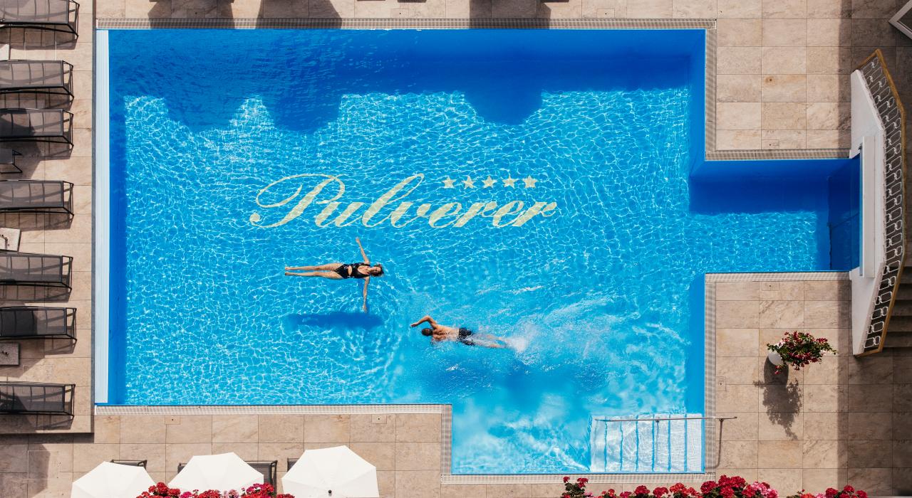Foto aus der Luft von zwei Personen, die im Außenpool im Thermenhotel in Kärnten schwimmen