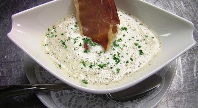 Eine cremige Suppe in einer weißen Schale, garniert mit gehackten Kräutern