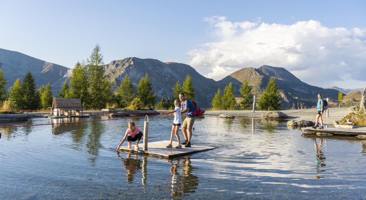 Eine Familie steht w&auml;hrend ihres Sommerurlaubs in K&auml;rnten auf einer Holzplattform im See