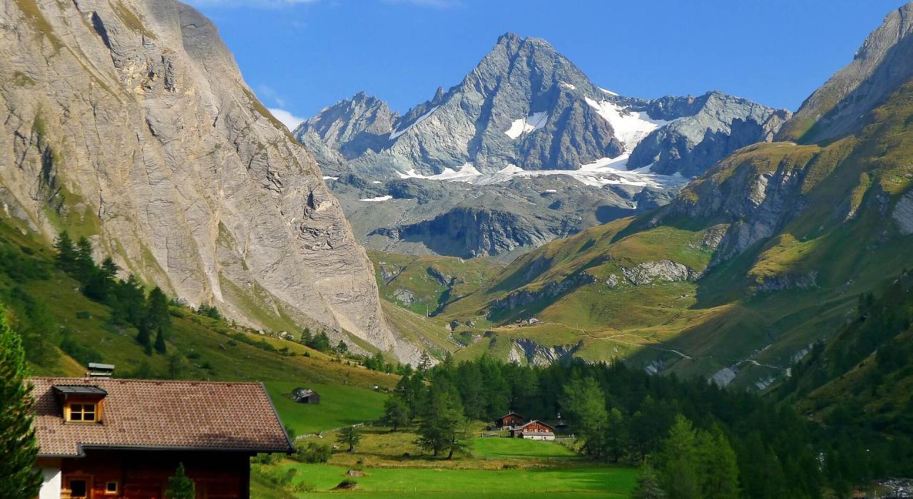 c0ab1ab9-ec3a-4f7d-ad00-163b8b2d11ff Eine malerische Alpenlandschaft mit grünen Tälern, steilen Felsen und schneebedeckten Gipfeln