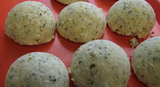 Fuelle-Kasnudel Runde, grüne, körnige Knödel auf einer roten Platte