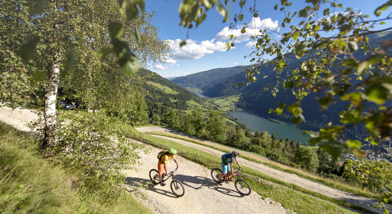 Zwei Personen beim Mountainbiken in Bad Kleinkirchheim genie&szlig;en den Blick auf den See und die Natur