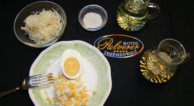 DSCF0176 Ein Teller mit gehacktem Ei, geriebener Käse, Salz, zwei Gläser Wein, und ein Hotel Pulverer Thermenwelt Untersetzer