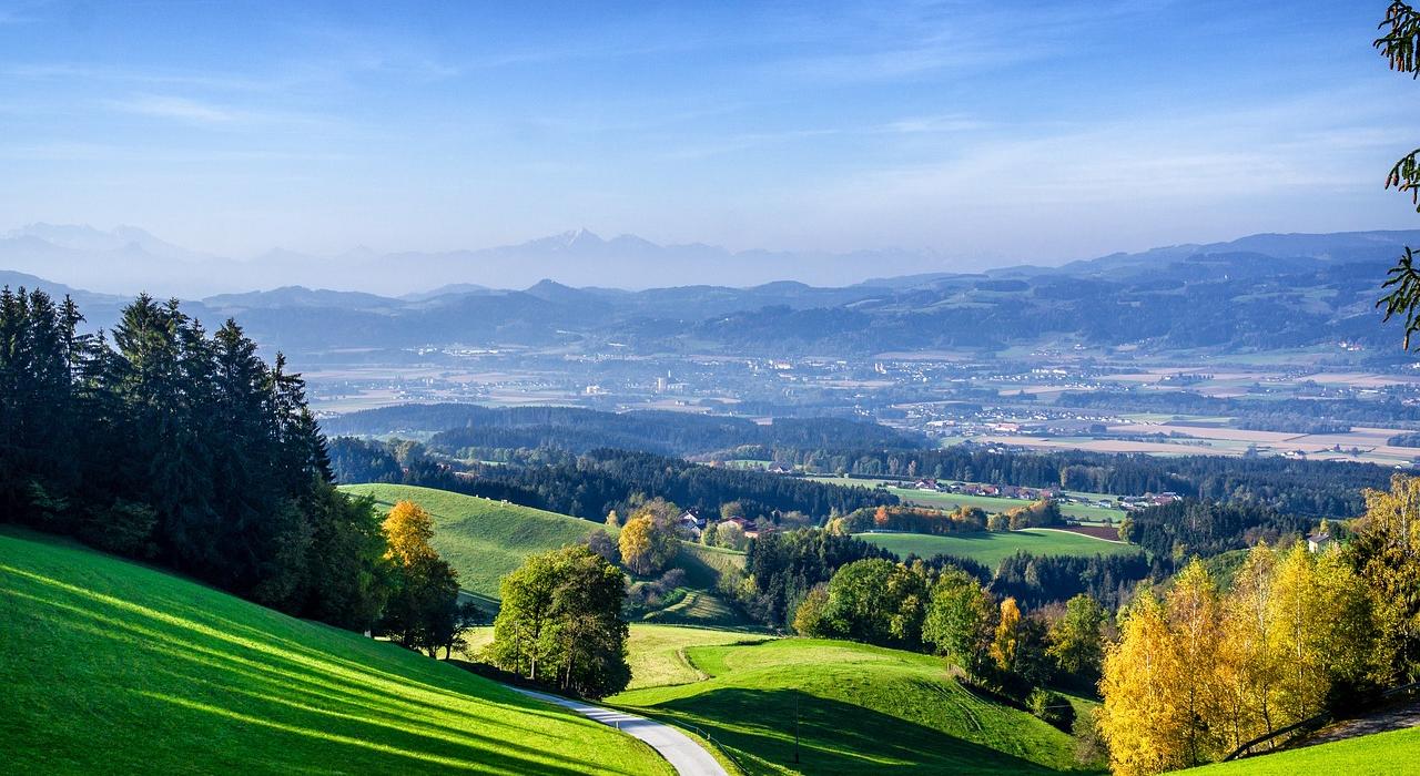 82955e52-e708-481b-a507-ce5a55130e70 Eine malerische Landschaft mit grünen Hügeln und Wäldern