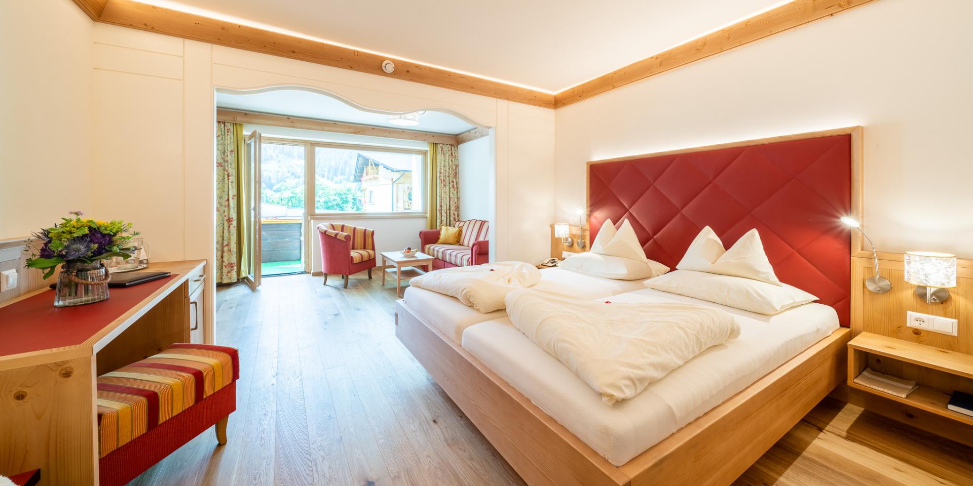 20--web_hotel_pulverer_zimmer_copy_gert_perauer Blick auf ein Bett und eine Sitzecke im Zimmer des 5 Sterne Hotels in Bad Kleinkirchheim