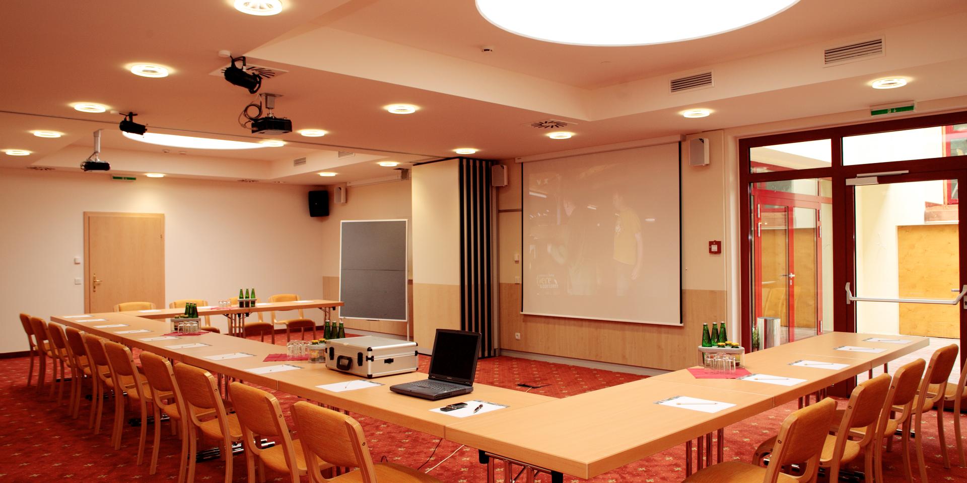 09_seminar94 Blick in den Konferenzraum mit Konferenztisch und Stühlen in Richtung Projektor im Seminarhotel in Kärnten