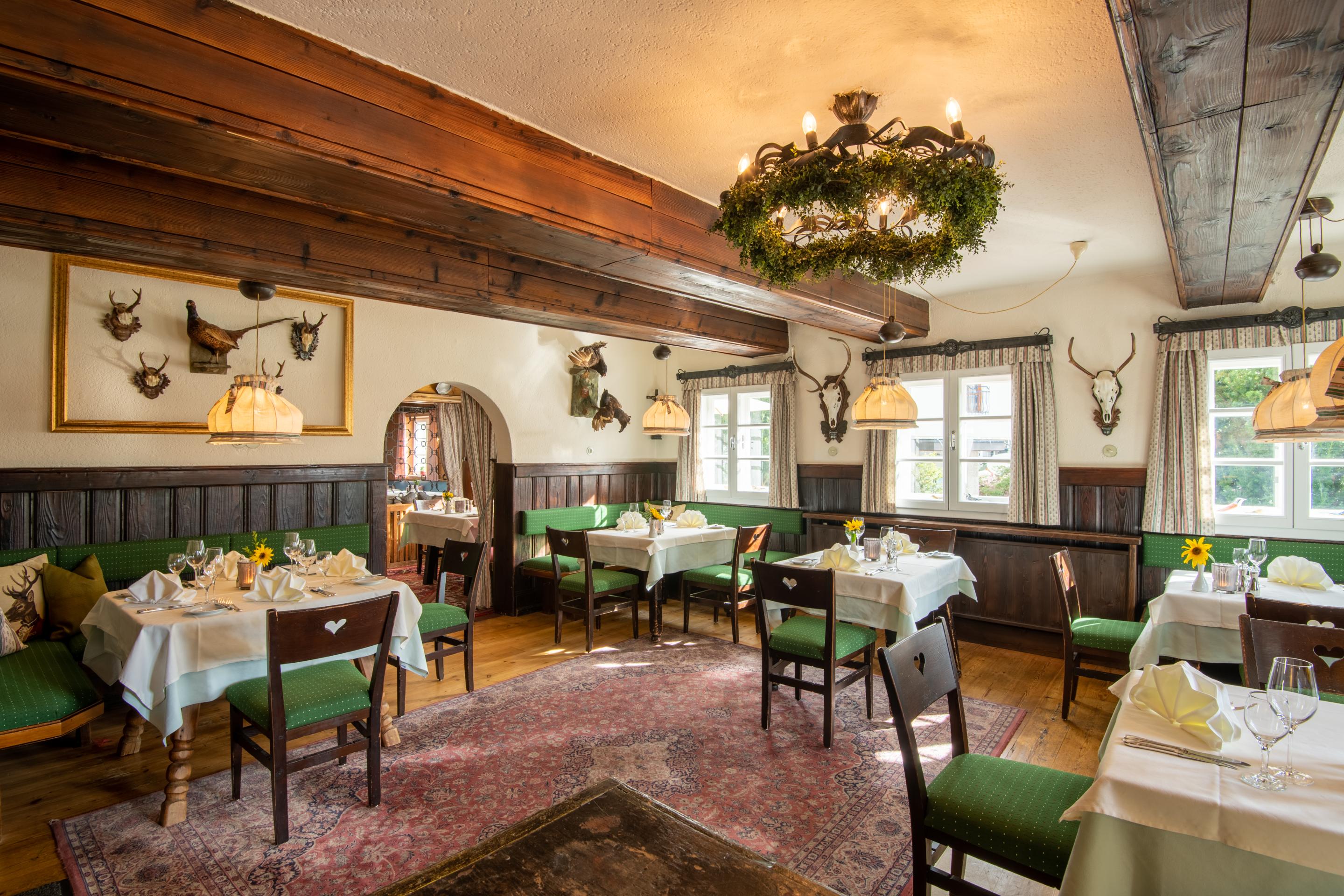 Der Blick auf das Restaurant Loystub'n, die Eventlocation in Kärnten, mit grünen Sitzmöbeln im Retrostil
